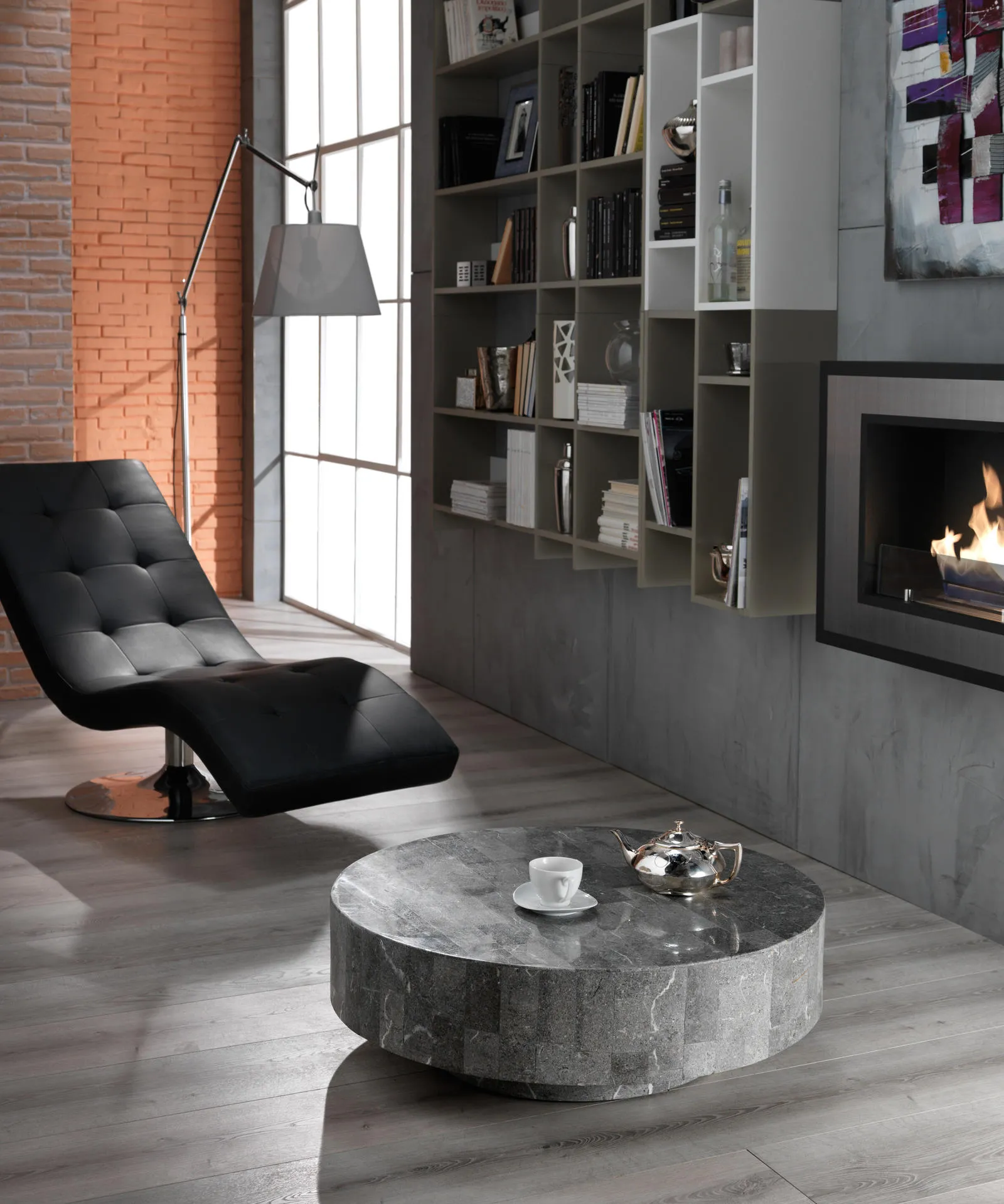 Tavolino Round 1 Stones grigio accanto a una chaise longue nera