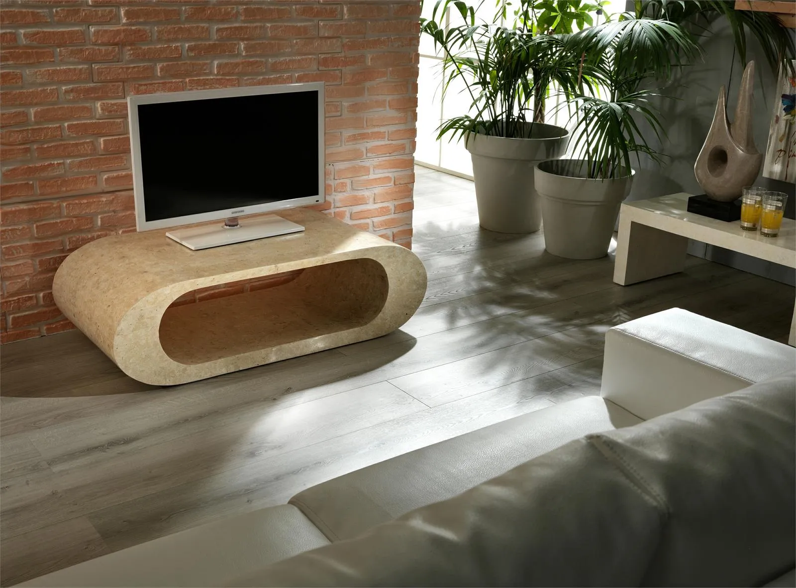 Tavolino Sandu Stones in pietra beige usato sotto la TV davanti a una parete di mattoni