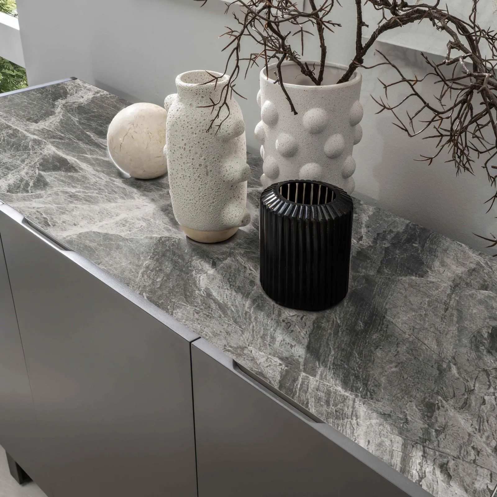 Dettaglio del top in ceramica marmo grigio della madia Pegaso Stones con vasi