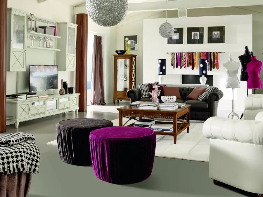 Tavolino quadrato Tosato 22.61 carico di libri in un loft con travi bianche, pouf viola e poltrona Chesterfield