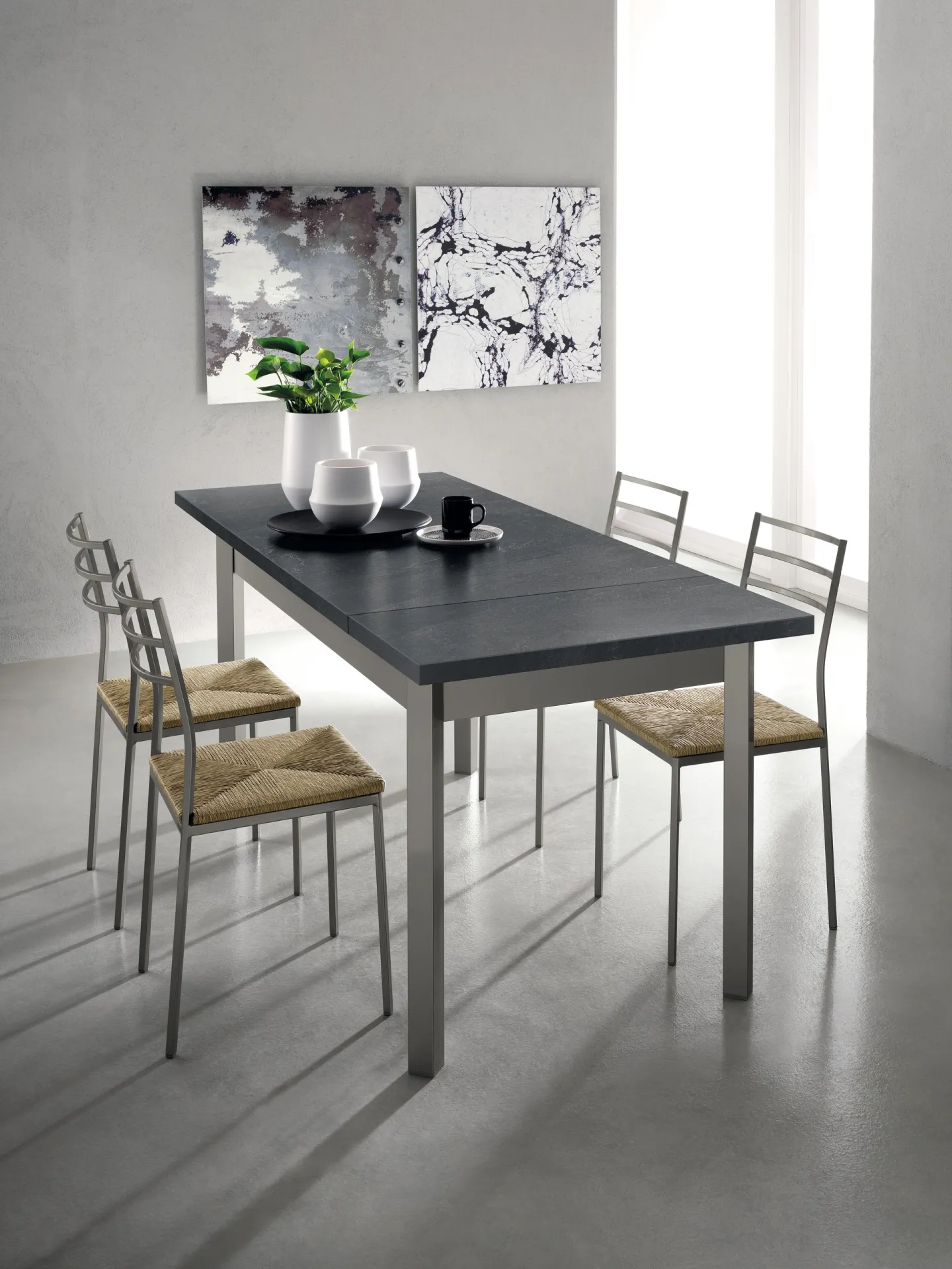 Tavolo Duetto Scavolini allungato con piano nero e sedie impagliate vicino alla finestra