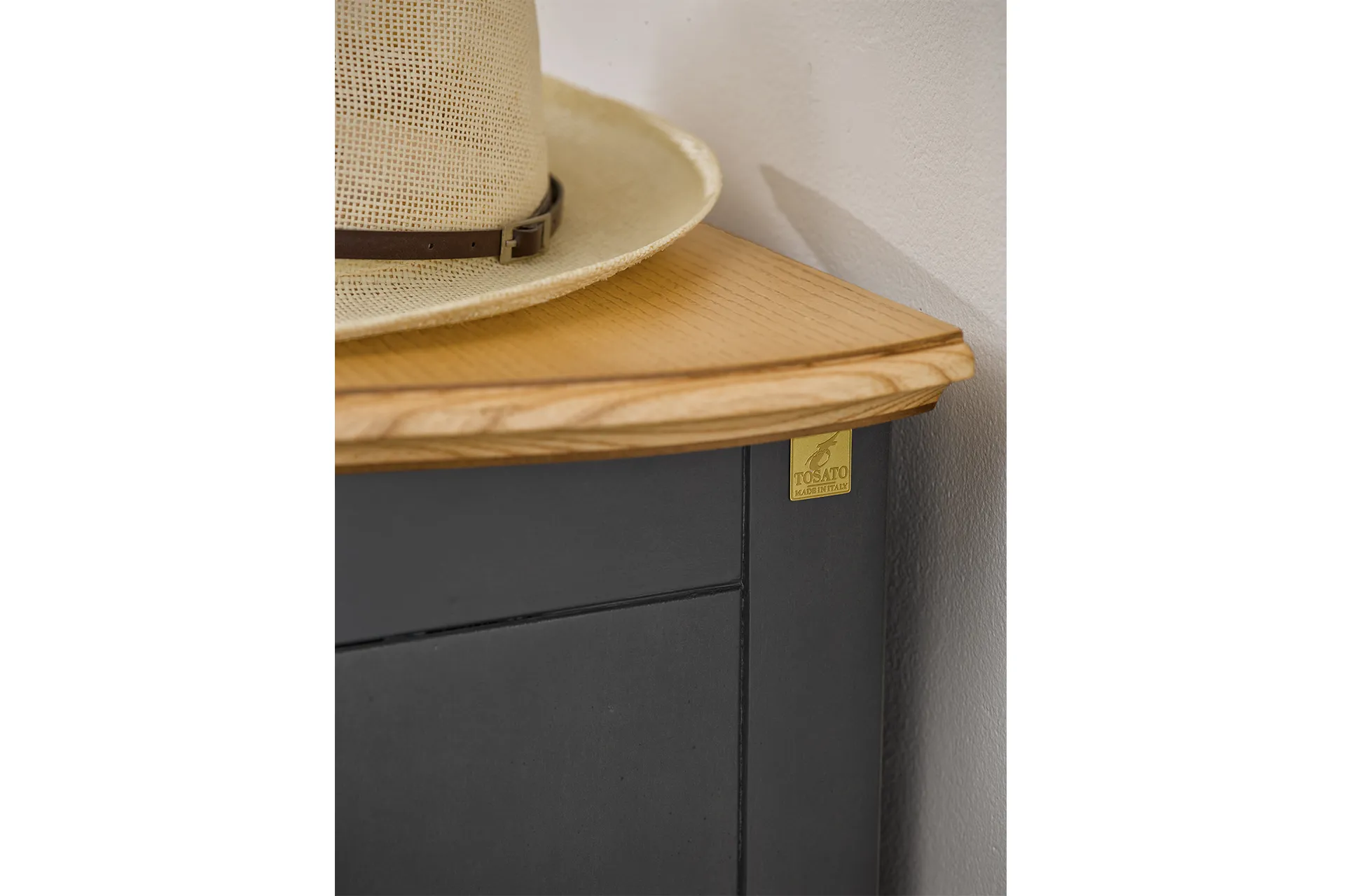 Piano in legno chiaro e fianco scuro della vetrina Tosato 16.79, con un cappello