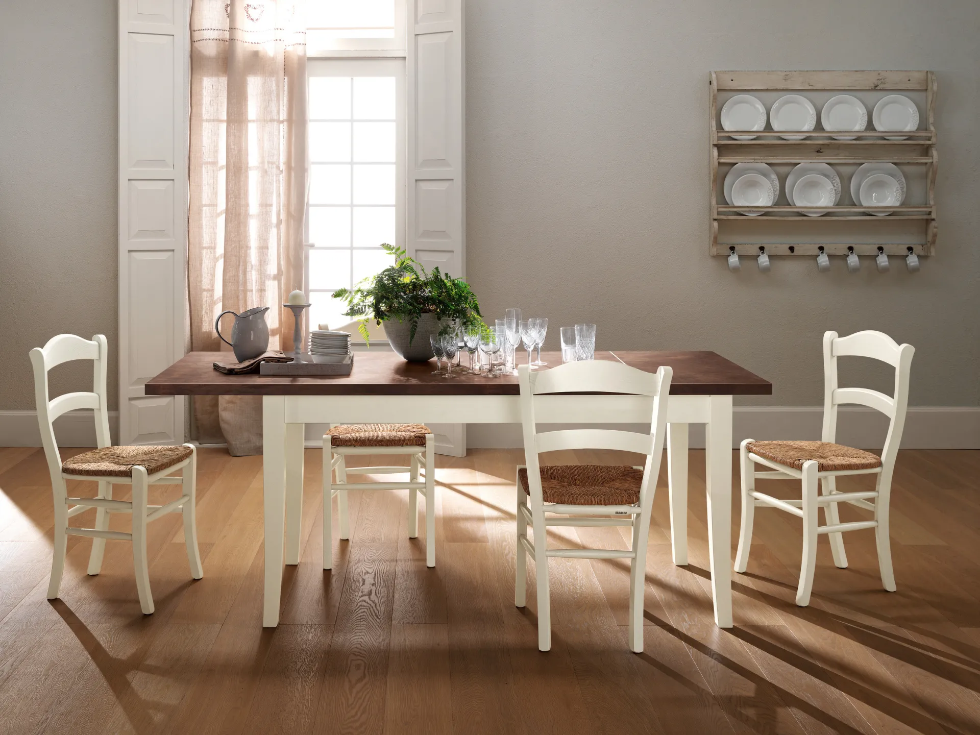 Tavolo Margot Scavolini con piano color noce, gambe bianche e sedie impagliate in una cucina rustica