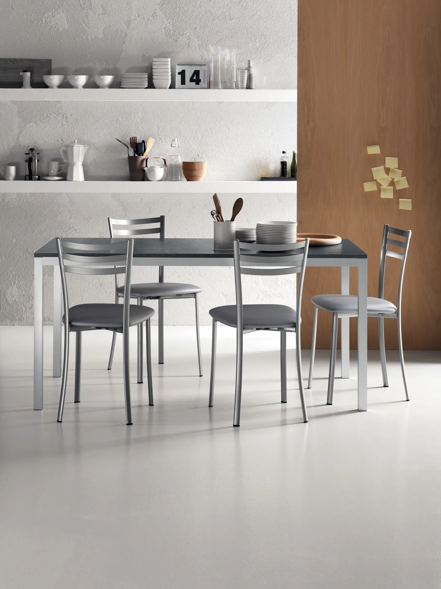 Tavolo Speedy Scavolini con struttura argento, piano grigio scuro e sedie in metallo in una cucina chiara