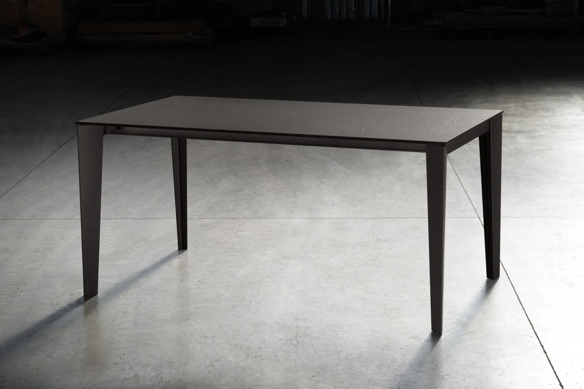 Tavolo Mary Scavolini grigio antracite con gambe rastremate in un ambiente dalle luci soffuse