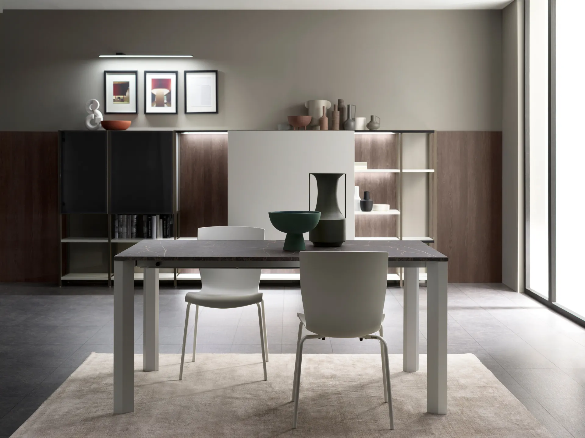 Tavolo Flawless Scavolini con piano scuro venato e gambe grigie davanti a una parete attrezzata in legno