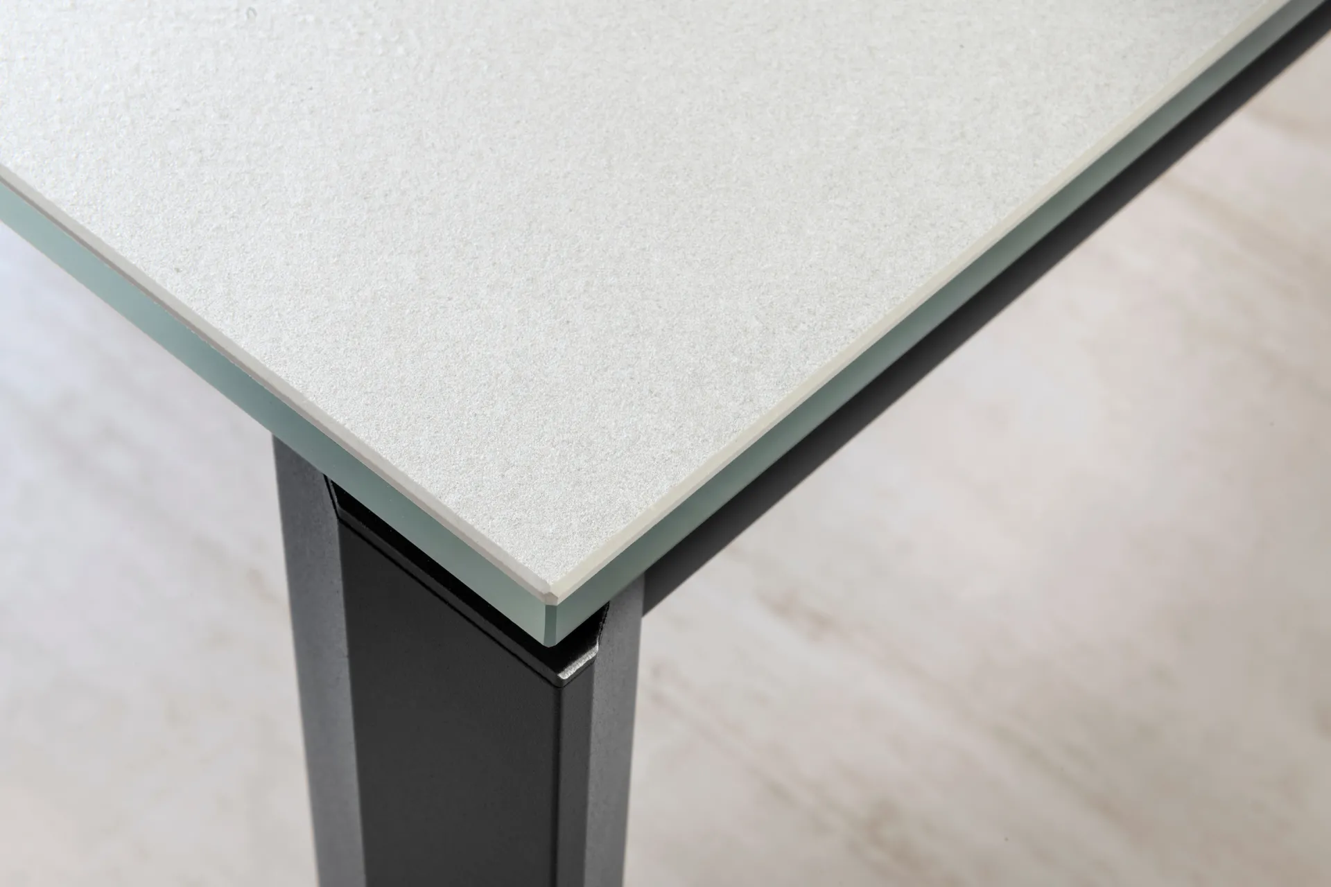 Dettaglio dello spigolo del tavolo Flawless Scavolini con piano in gres su vetro e gamba scura