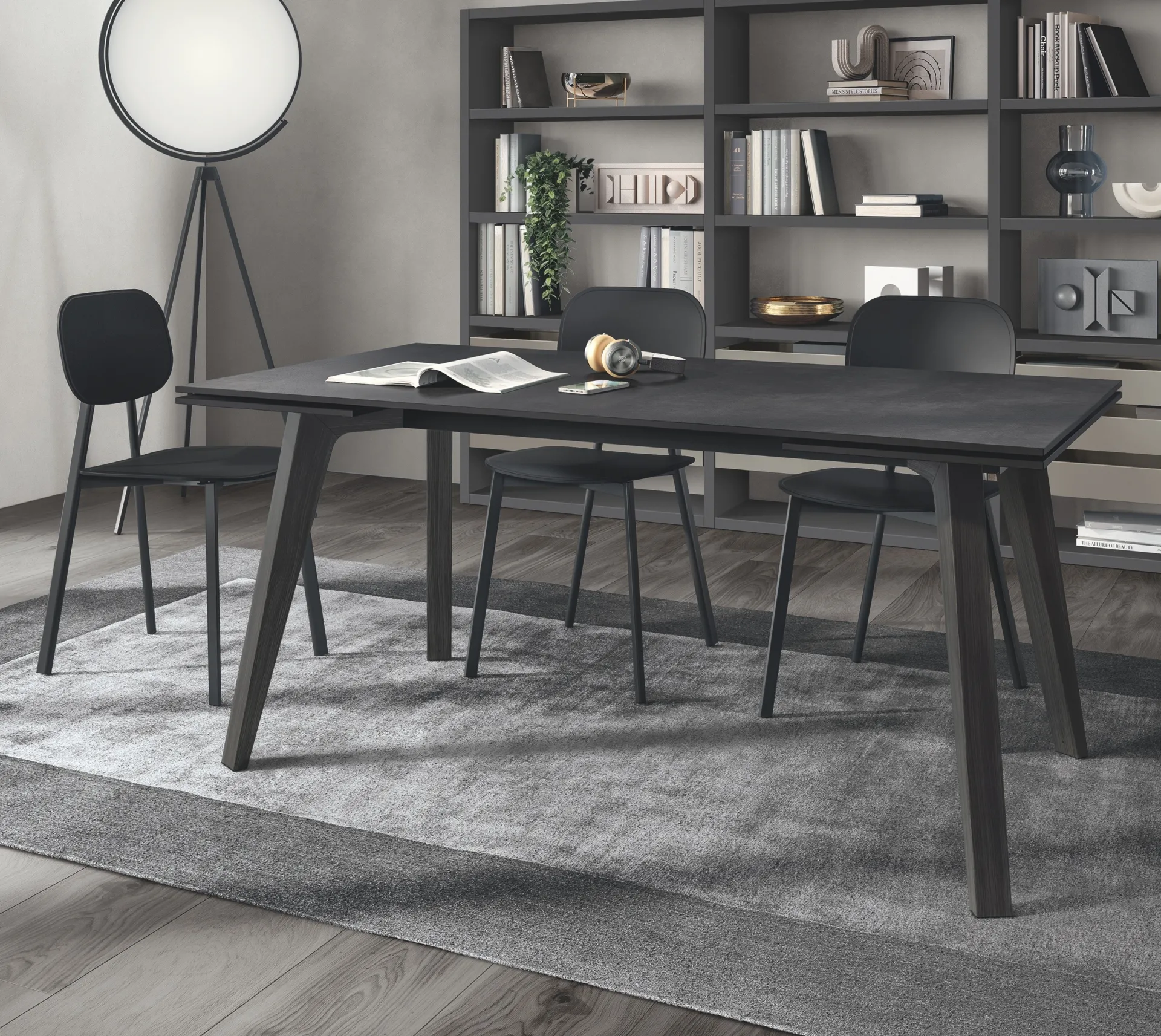 Tavolo Motus Scavolini scuro con gambe in rovere Carbone e sedie nere davanti a una libreria