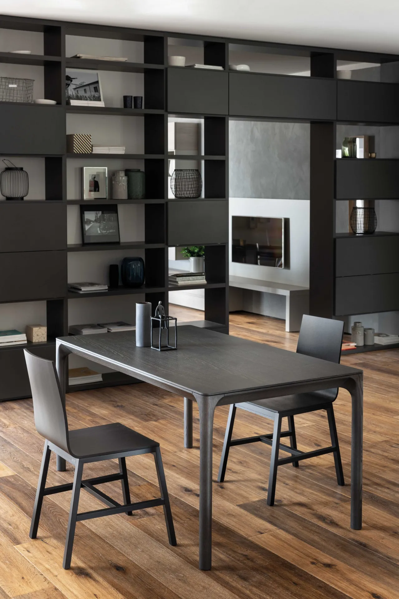 Tavolo Kei Scavolini in frassino scuro con due sedie davanti a una libreria