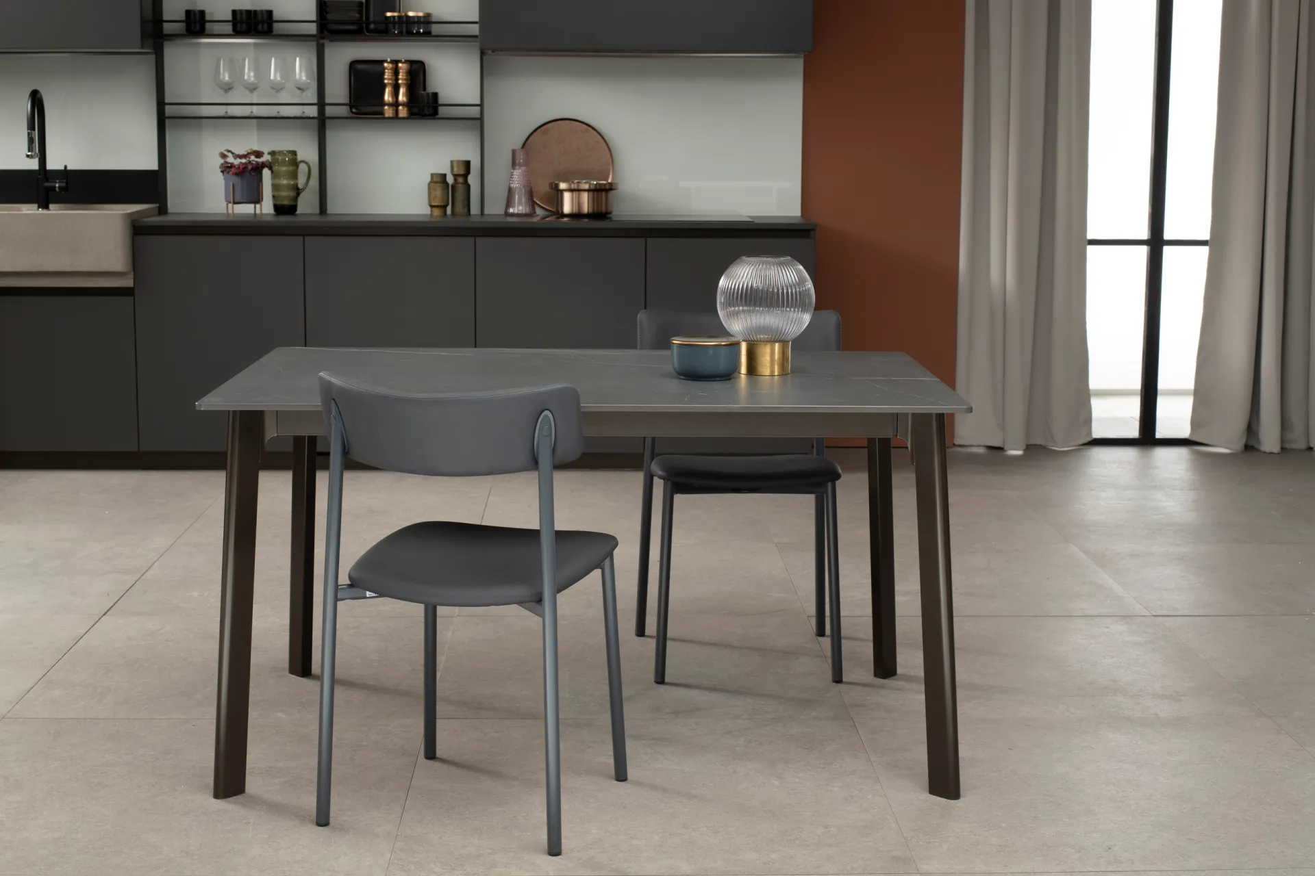 Tavolo Norwegian Scavolini scuro con piano grigio e sedie grigie in una cucina con mensole