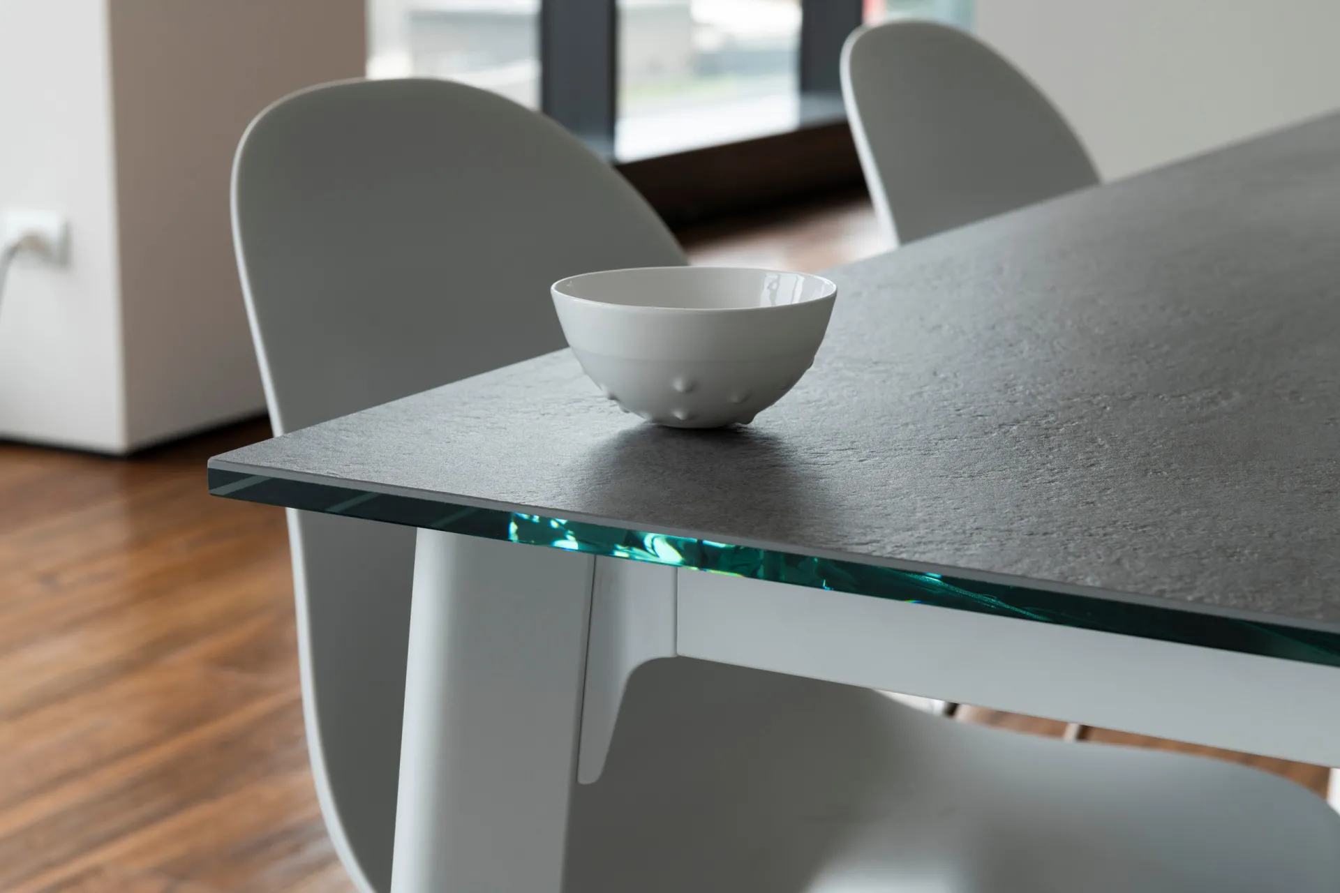 Dettaglio del tavolo Norwegian Scavolini con piano scuro su vetro dal bordo verde e struttura bianca