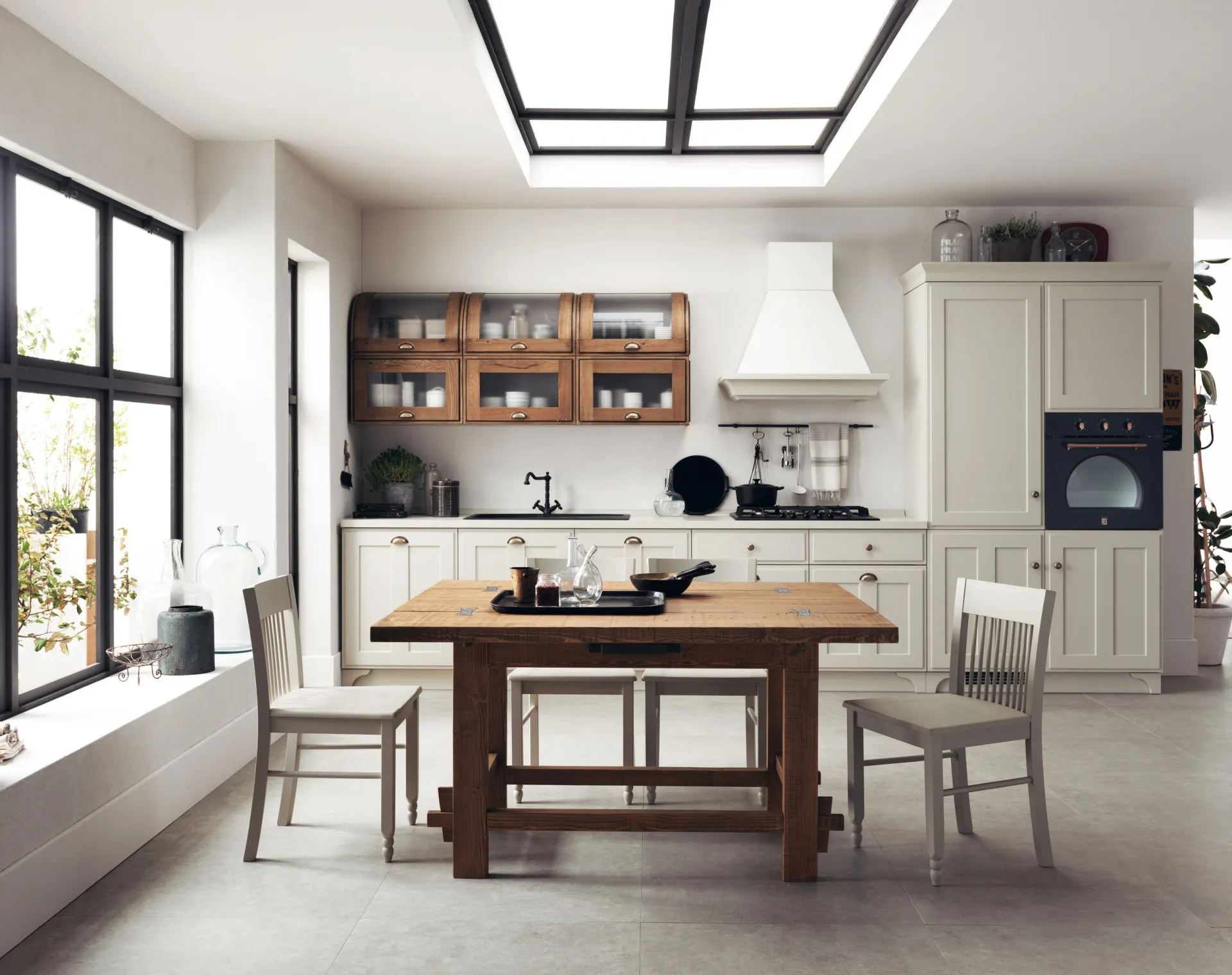 Tavolo Tabula Scavolini in abete massello al centro di una cucina classica chiara sotto un lucernario