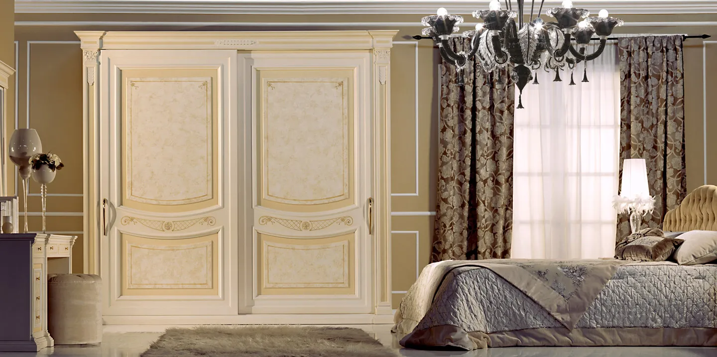 Armadio Teseo Bernazzoli a due ante con decori ocra in camera con letto