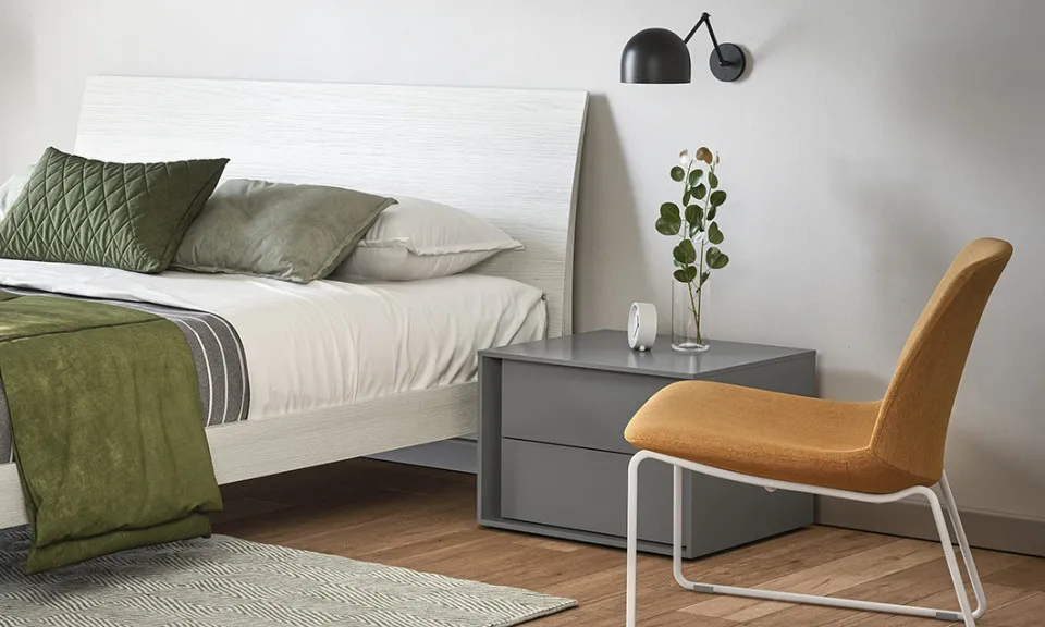 Comodino Bilbao Cinquanta3 grigio accanto al letto con poltroncina gialla