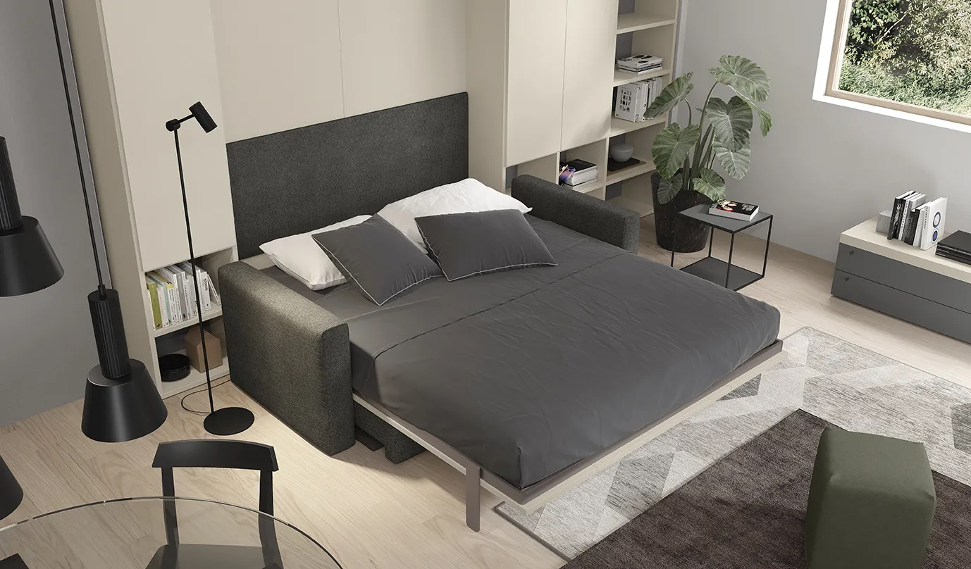 Letto Click Colombini con testata grigia aperto accanto a un divano nella stessa parete attrezzata