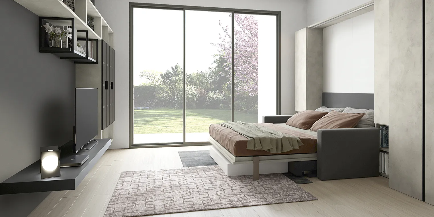 Letto a scomparsa Click Colombini aperto davanti a una parete TV in un open space con vetrata