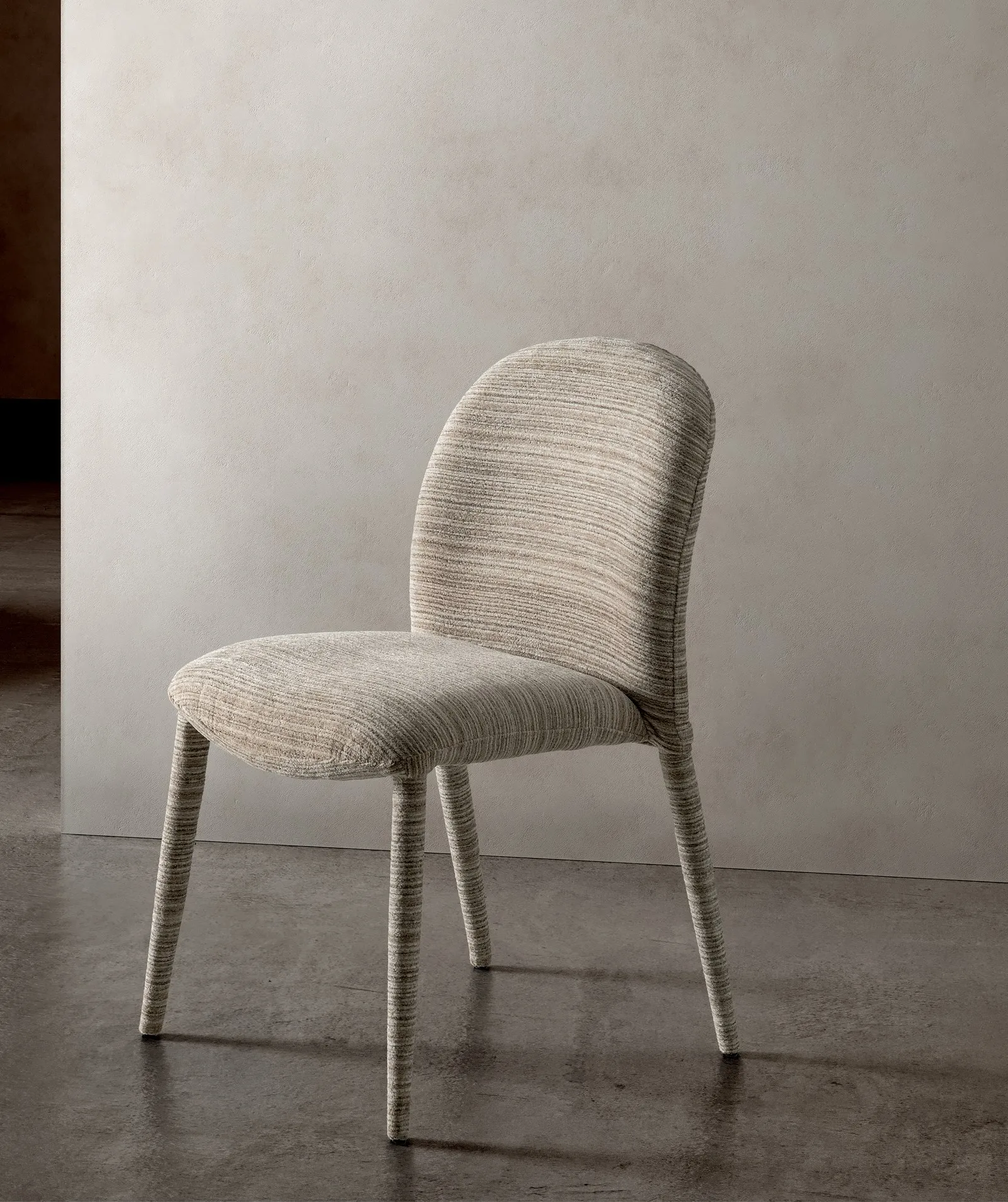 Sedia Antea Stones in tessuto beige striato con gambe rivestite, davanti a una parete chiara
