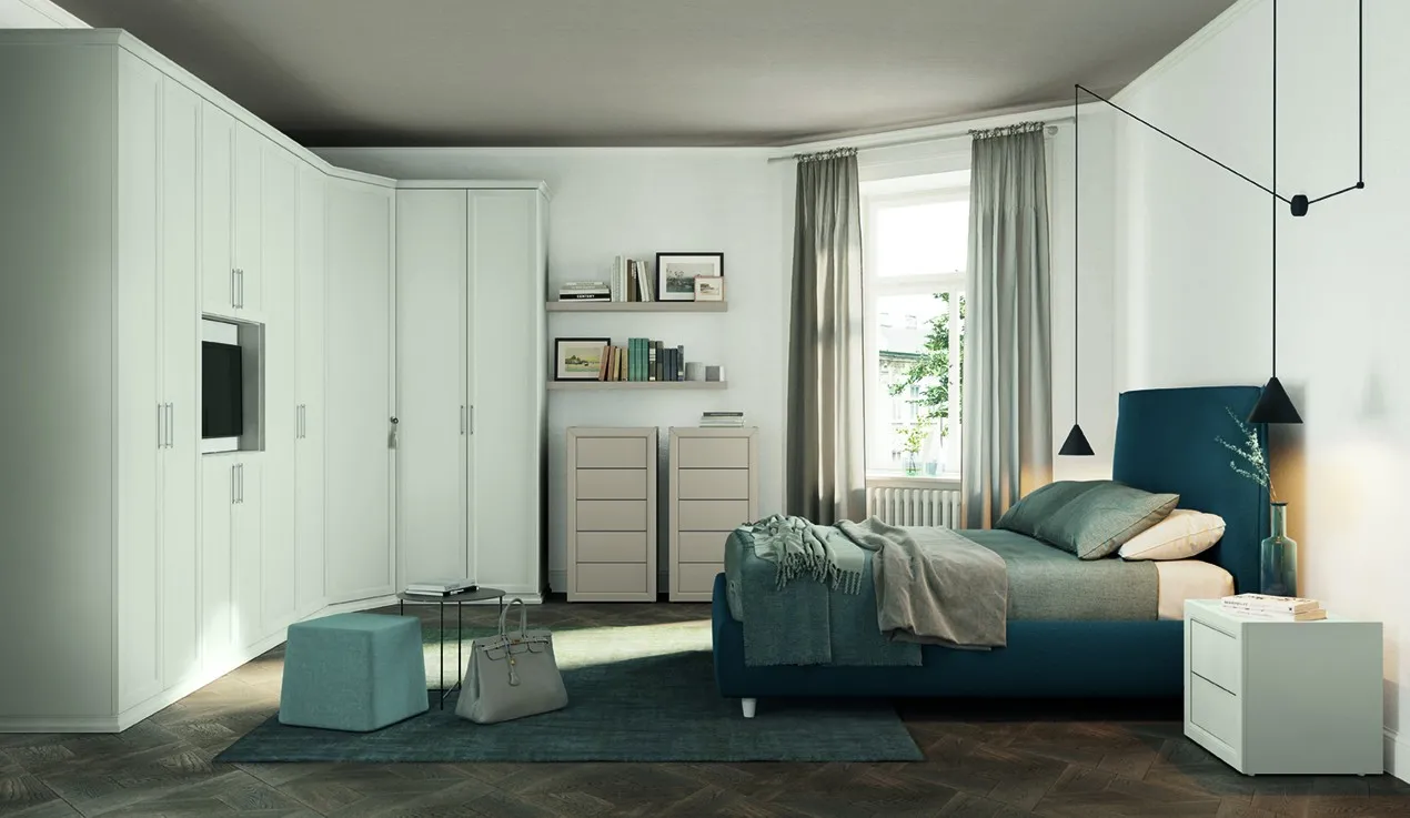 Letto Norma Colombini blu petrolio accanto a un comodino bianco e a una parete di armadi