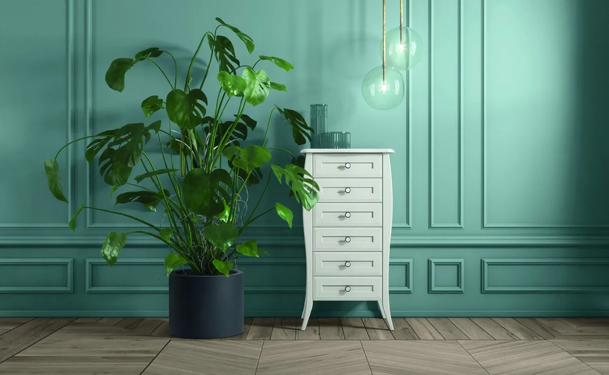 Settimino Shabby Chic Colombini bianco su gambe arcuate davanti a una parete azzurro petrolio