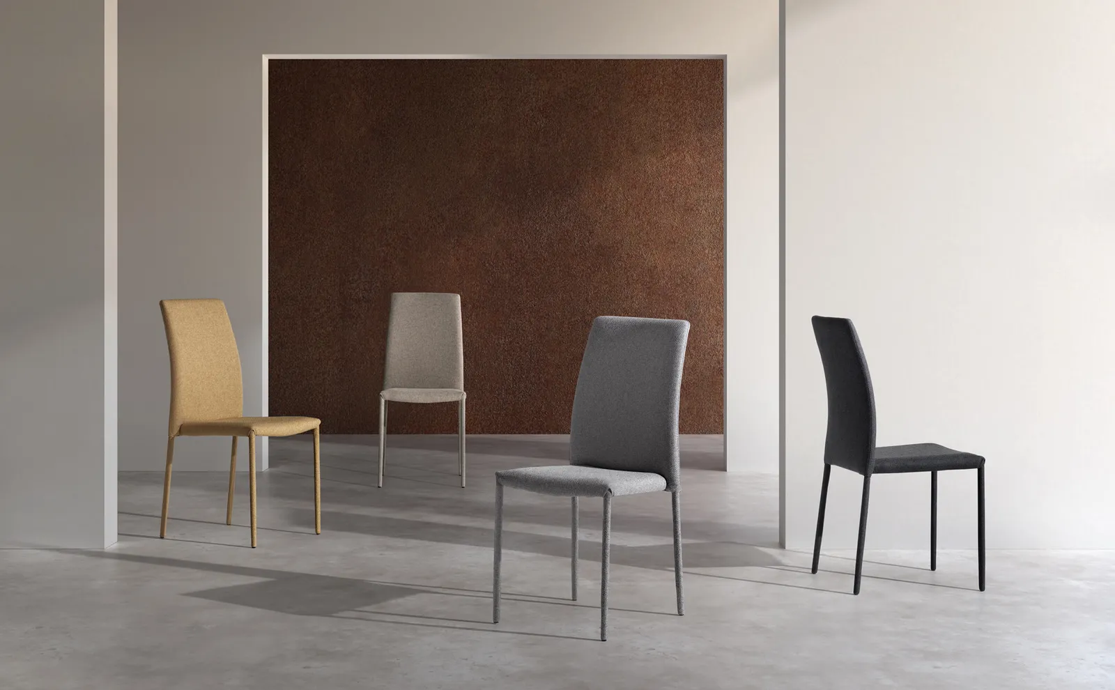 Quattro sedie Leda Stones nei colori giallo, beige, grigio scuro e nero davanti a un pannello color ruggine