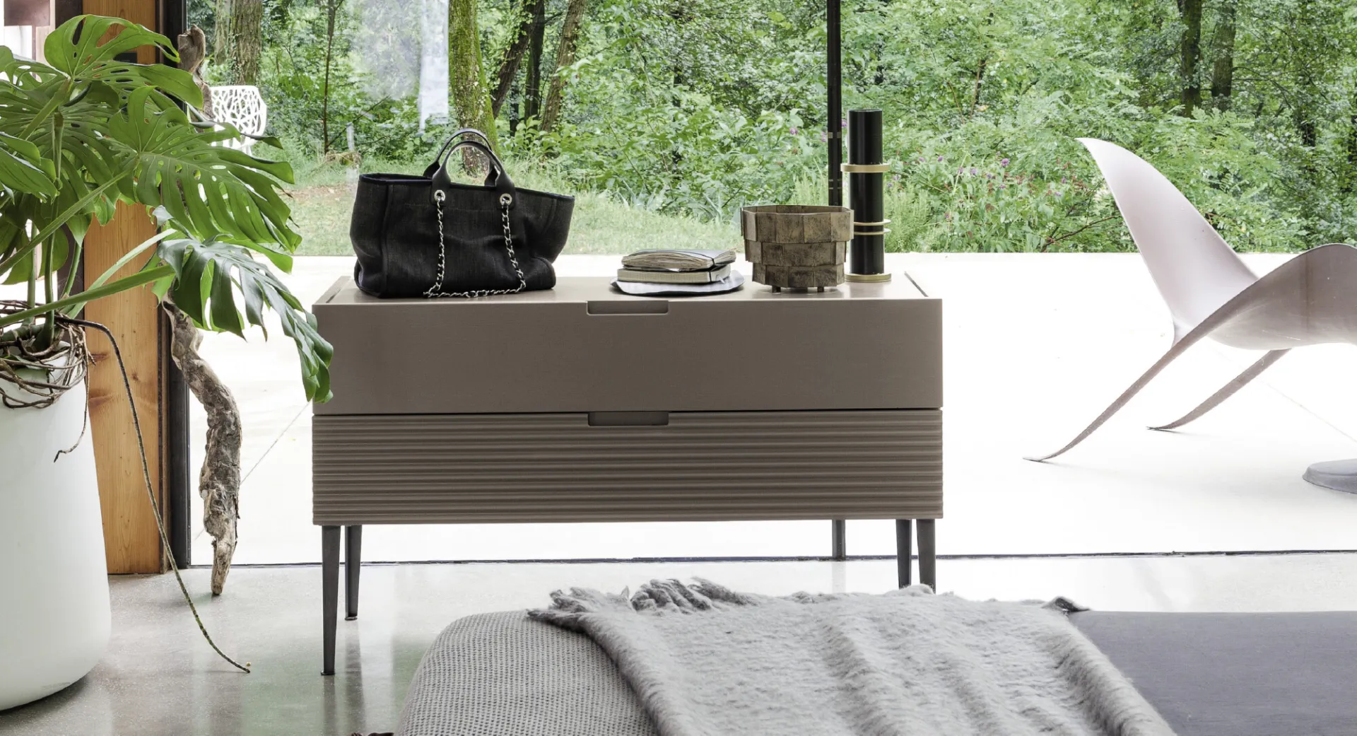 Comò Zero.16 Devina Nais a due cassetti cannettati davanti a una vetrata sul bosco
