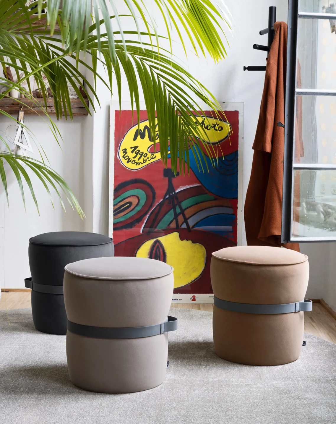 Tre pouf Pof Connubia in tessuto grigio, sabbia e cammello con cinghia scura in un soggiorno