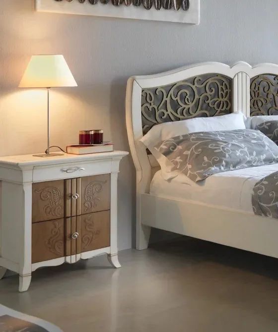 Comodino New Decò Francesco Pasi bianco con fronte nocciola a rilievo accanto al letto traforato