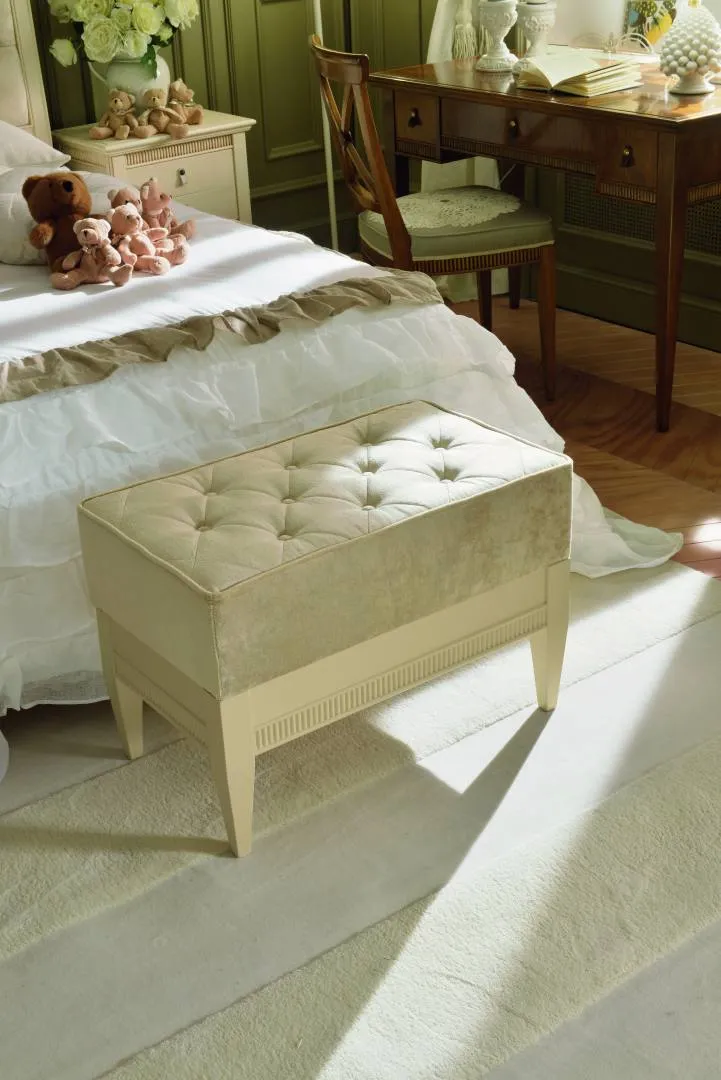 Pouf capitonné Tosato 51.03 color crema ai piedi di un letto con trapunta bianca