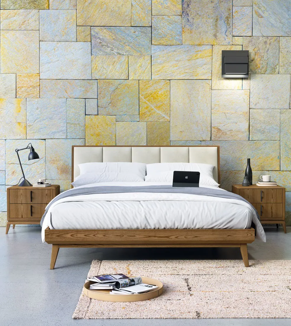 Letto Nova Linea Imba visto frontalmente davanti a una parete in pietra