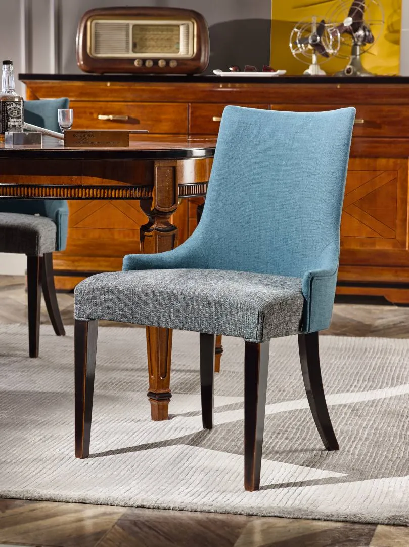 Sedia imbottita Tosato 50.26 in velluto azzurro con gambe nere, accanto a un tavolo in legno