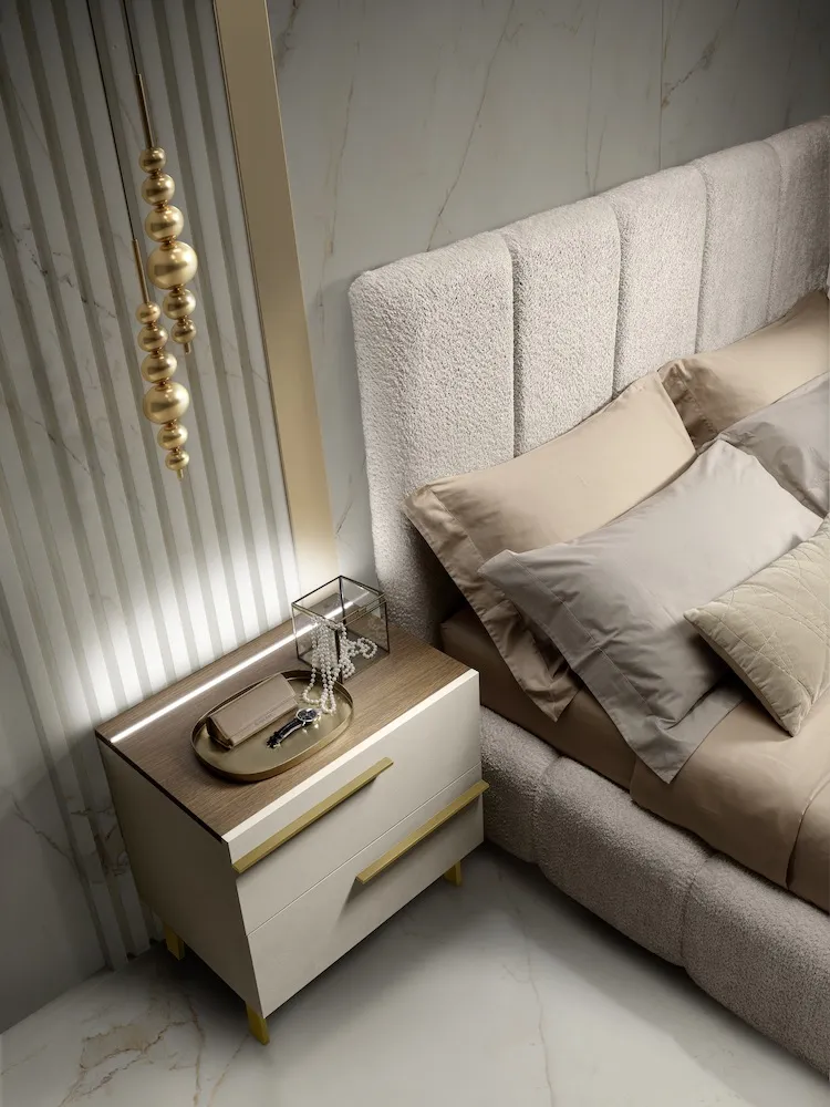 Comodino Rosa Luxury Mobilpiù con maniglia oro accanto al letto imbottito