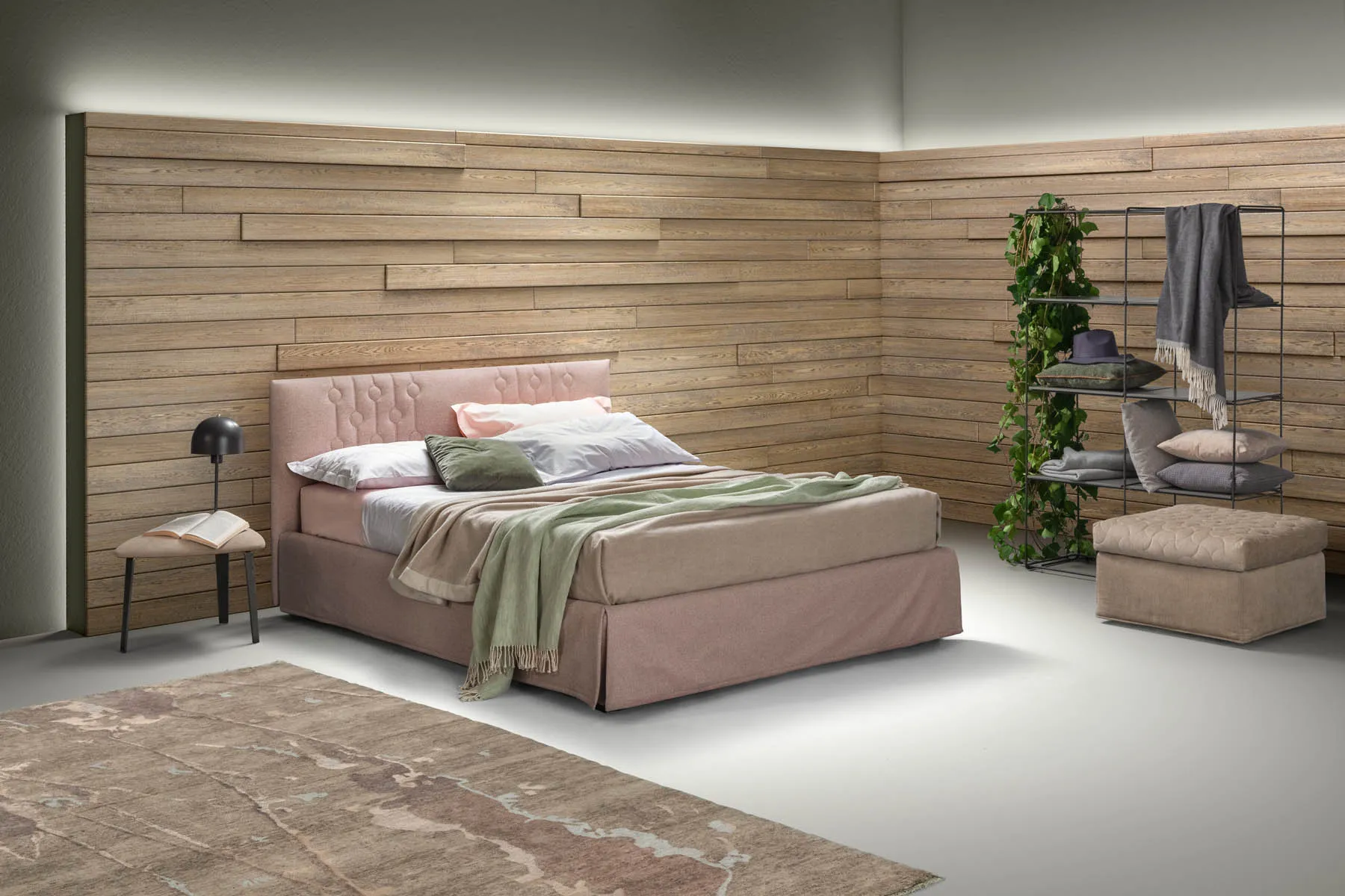 Letto matrimoniale Loop Samoa rosa antico con balza, davanti a una parete in doghe di legno