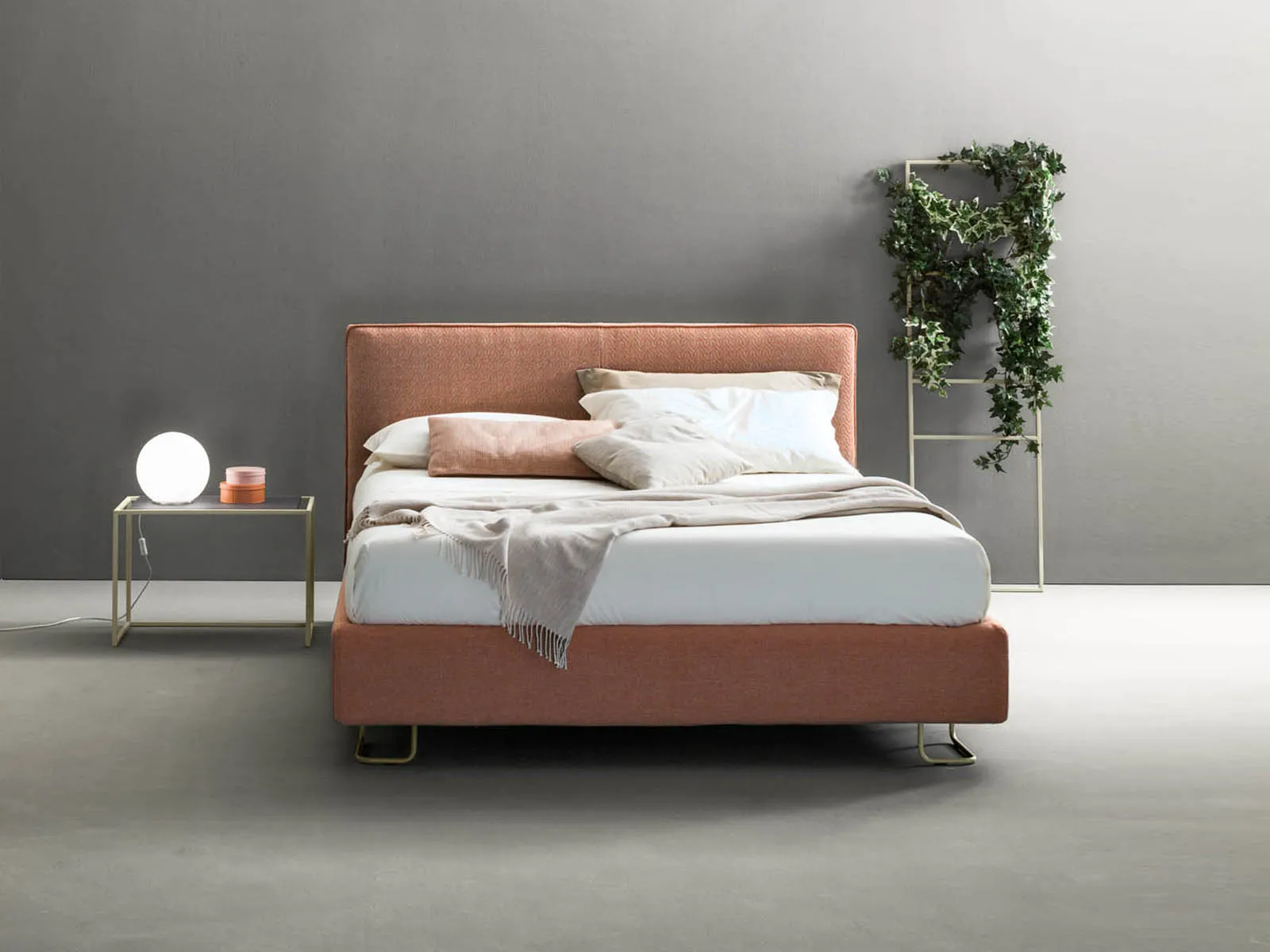 Letto matrimoniale Piping Samoa terracotta con bordino a contrasto, accanto a una scaletta con edera