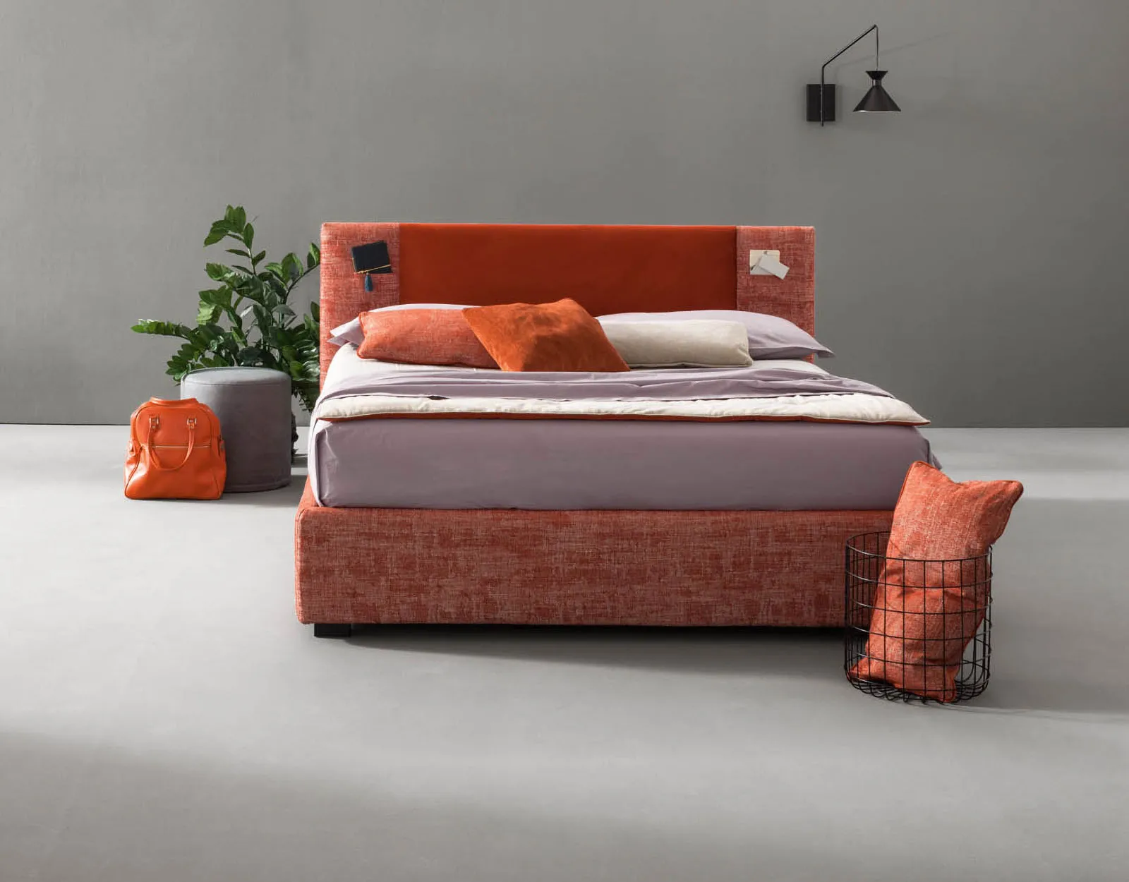 Letto matrimoniale Rift Samoa con testiera arancio e fianchi in melange rosso, accanto a una pianta