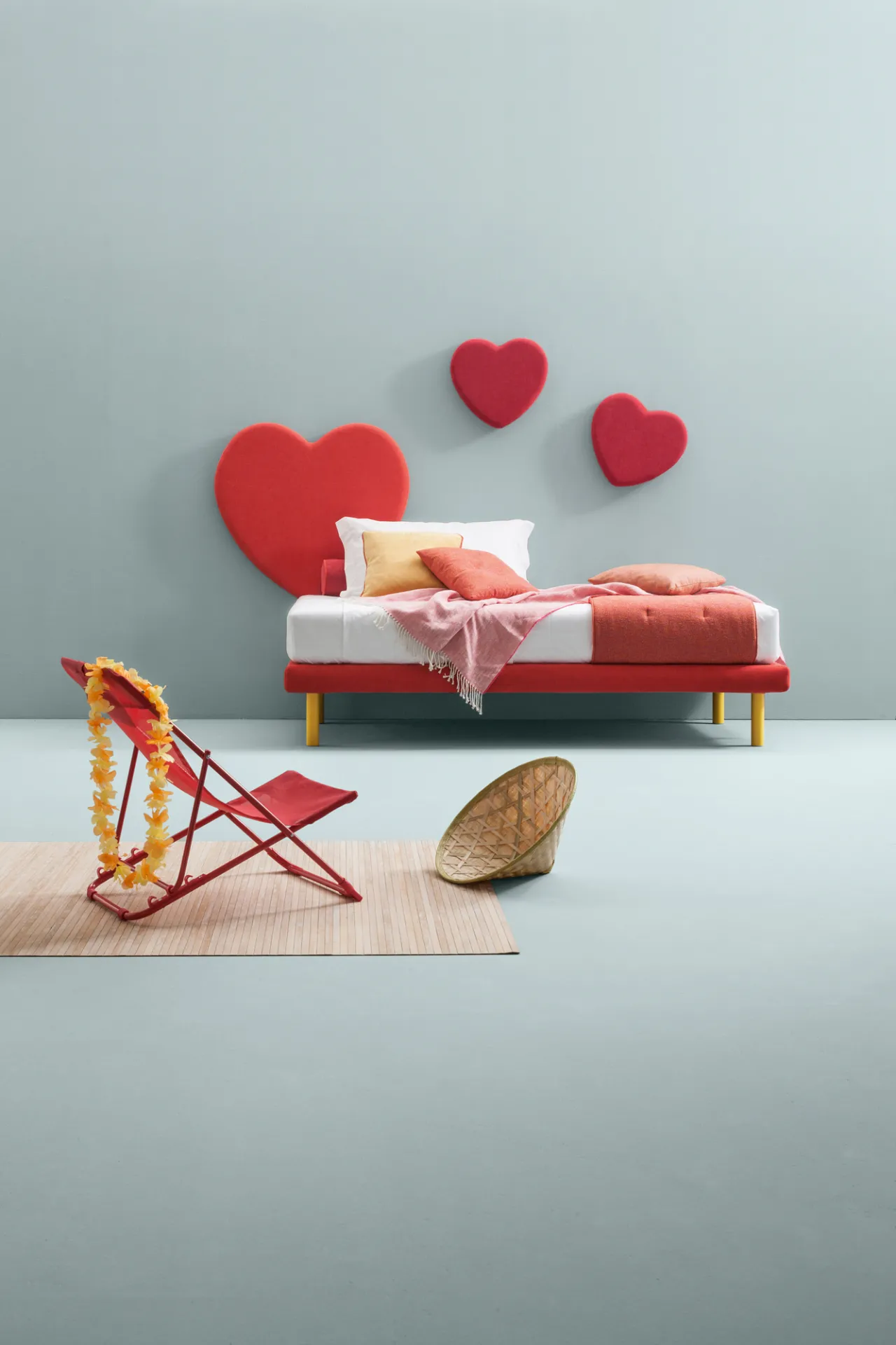 Cuori rossi Sweet Samoa alla parete dietro un letto, con una sdraio a righe davanti