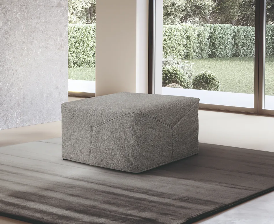 Pouf letto Celine San Lorenzo chiuso in tessuto grigio davanti a una vetrata
