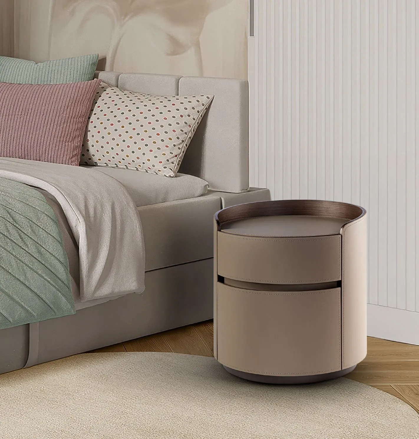 Comodino rotondo Circe Schuller in pelle beige con piano in marmo accanto a un letto imbottito
