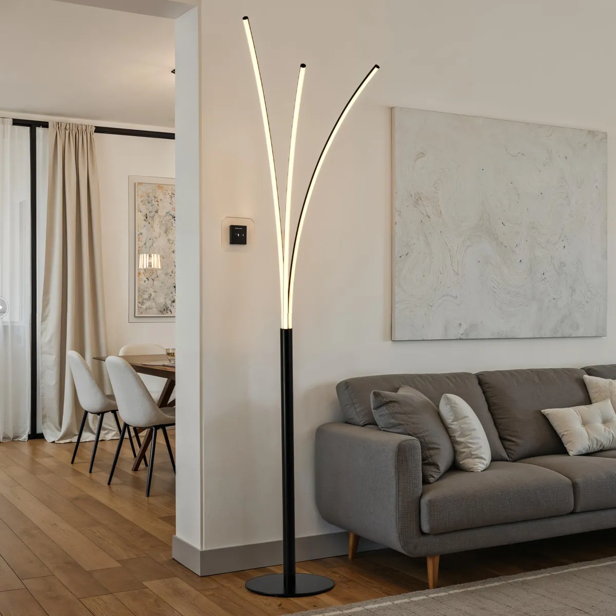 Lampada da terra Scratch Tomasucci con tre archi luminosi accesa in un soggiorno
