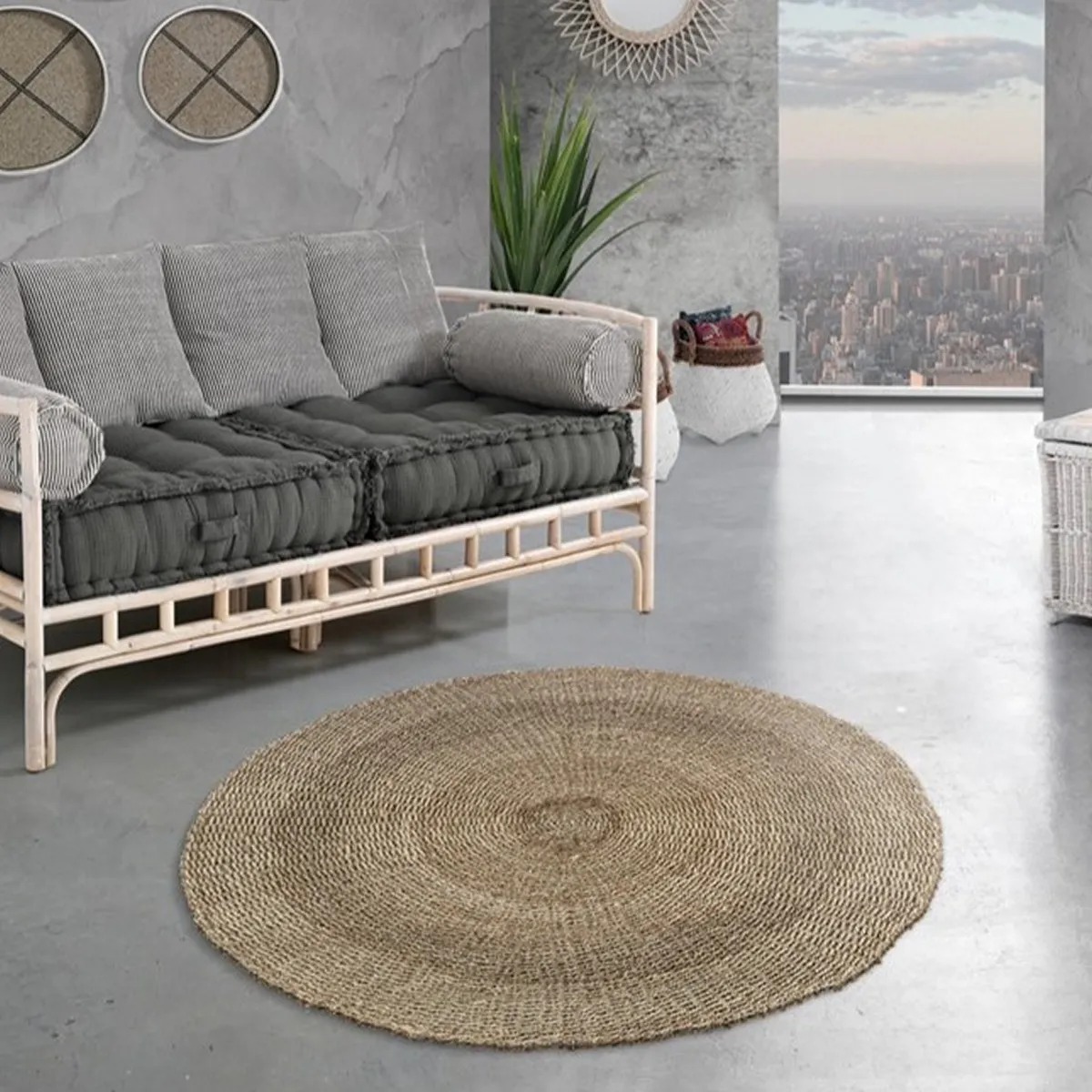 Tappeto rotondo Brahmi Tomasucci in seagrass davanti a un divano in rattan