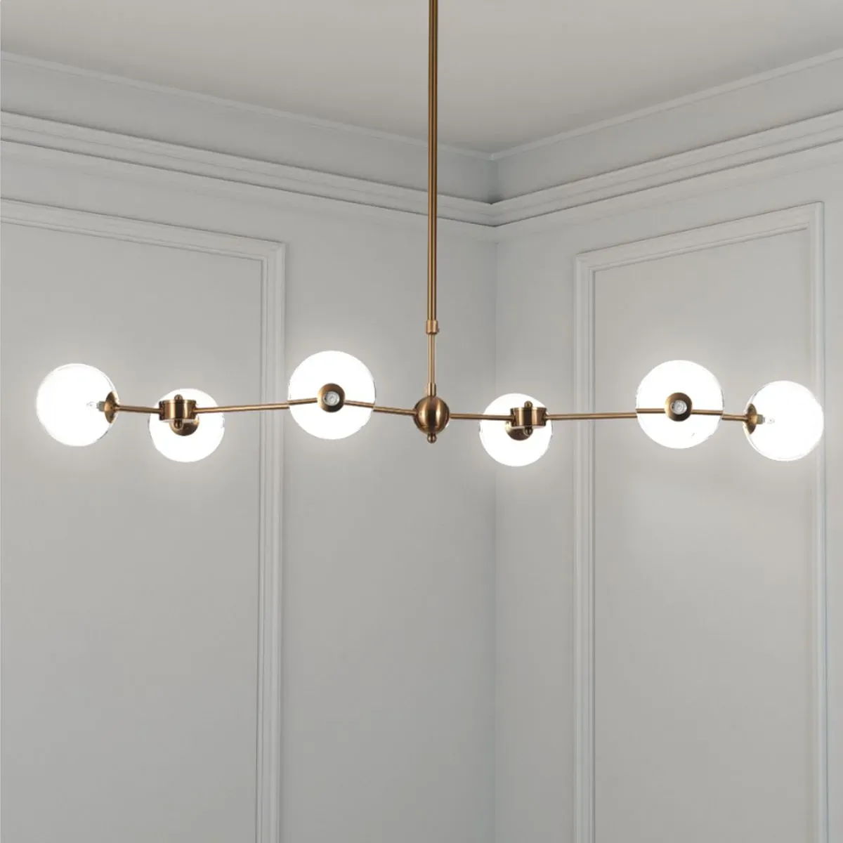 Lampadario Alycia Tomasucci in ottone con sfere in vetro bianco in una stanza chiara