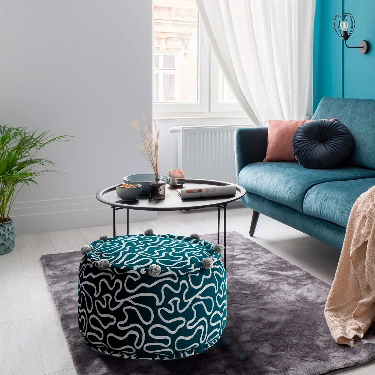 Pouf Tangle Tomasucci grigio e rosa davanti a un divano