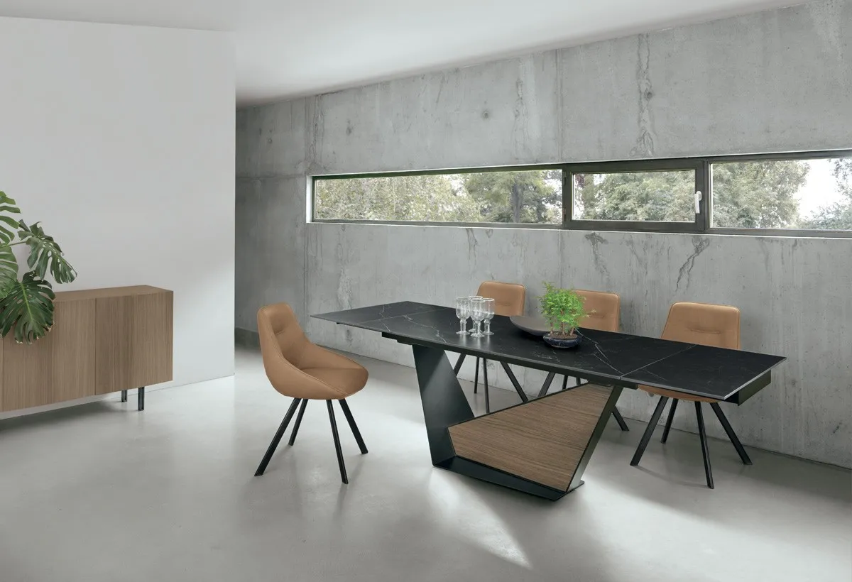 Tavolo Galeone Target Point con base in legno e sedie arancio in una sala con parete in cemento