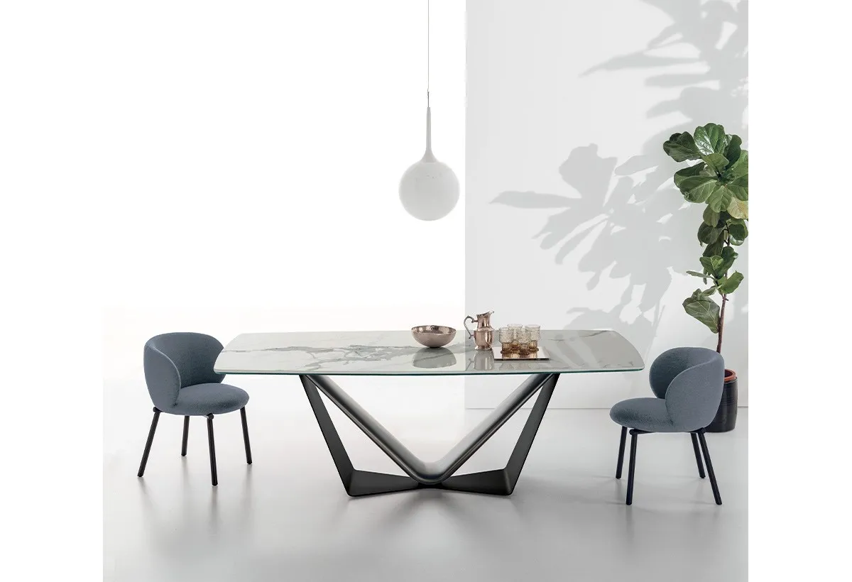 Tavolo Velar Target Point con piano effetto marmo e sedie blu sotto una lampada