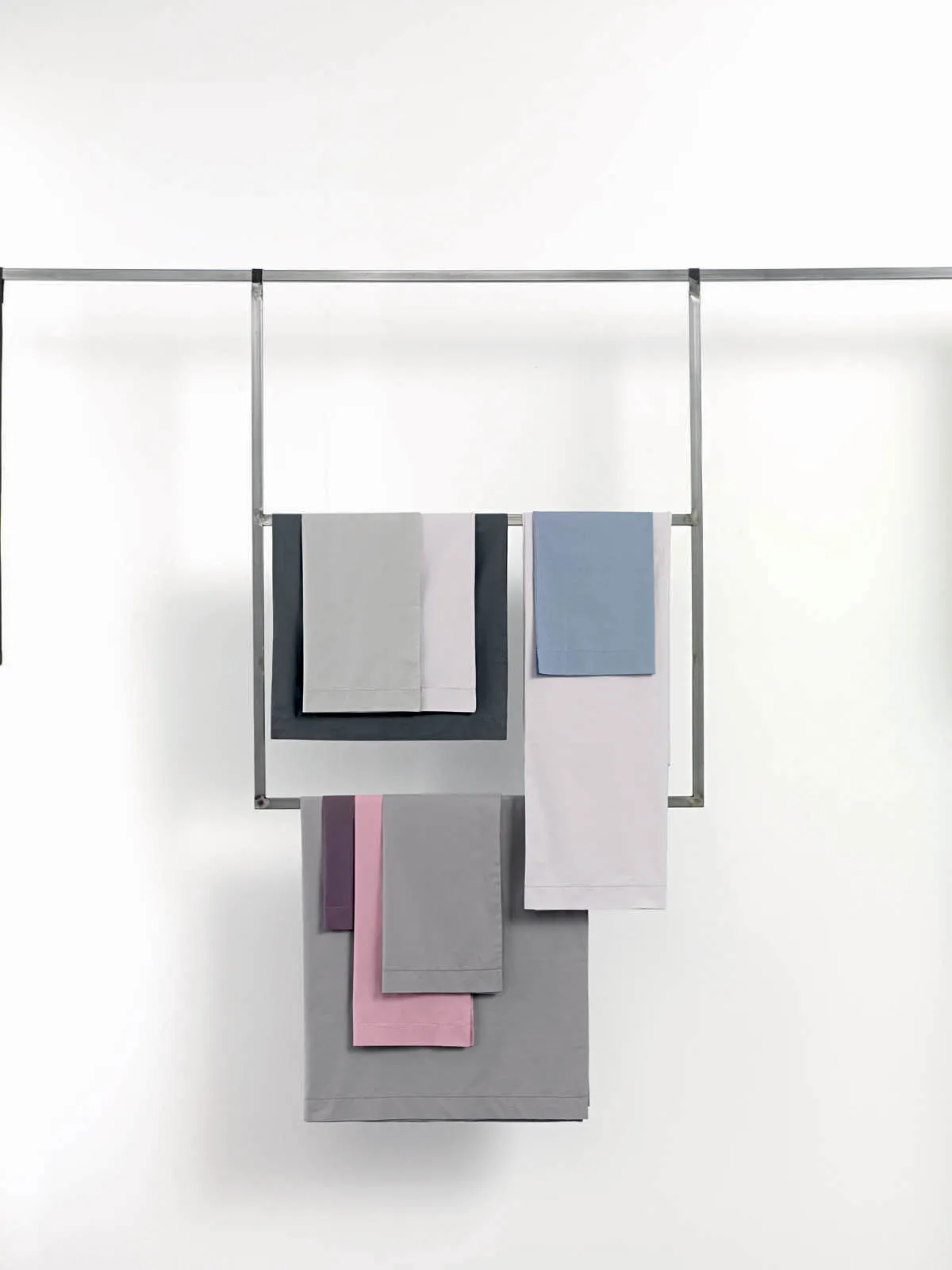 Biancheria da letto Samoa in cotone nei toni del grigio, azzurro, lilla e rosa, appesa a una barra