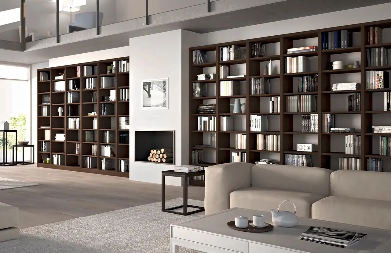 Parete libreria Melograno 25 Le Fablier scura ai lati di un camino in un soggiorno a doppia altezza