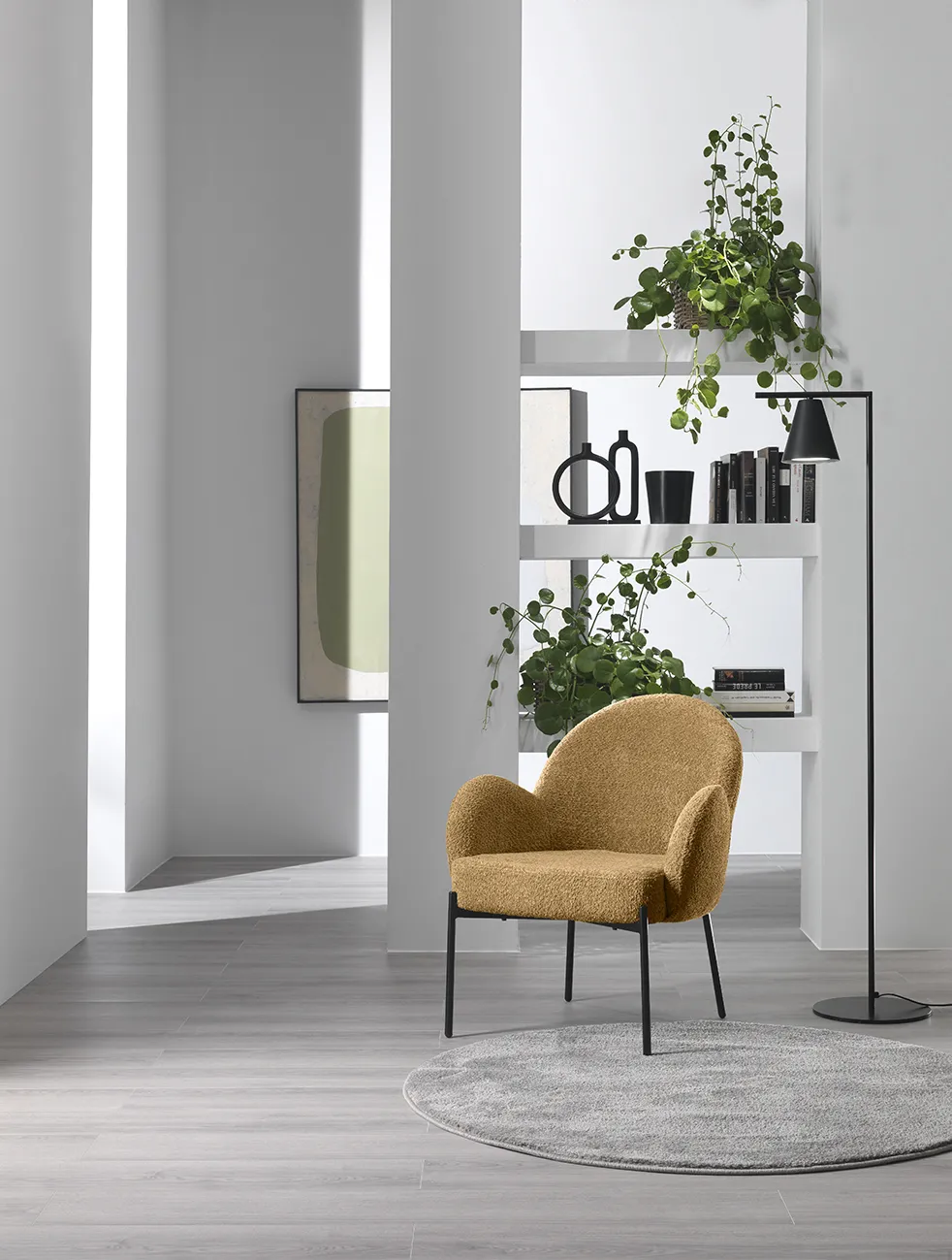 Poltrona Malibu Stones in bouclé color miele in un angolo del soggiorno con libreria e piante