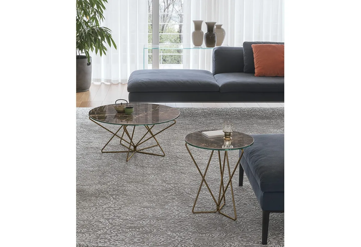 Tavolini Star Target Point con base dorata davanti a un divano blu