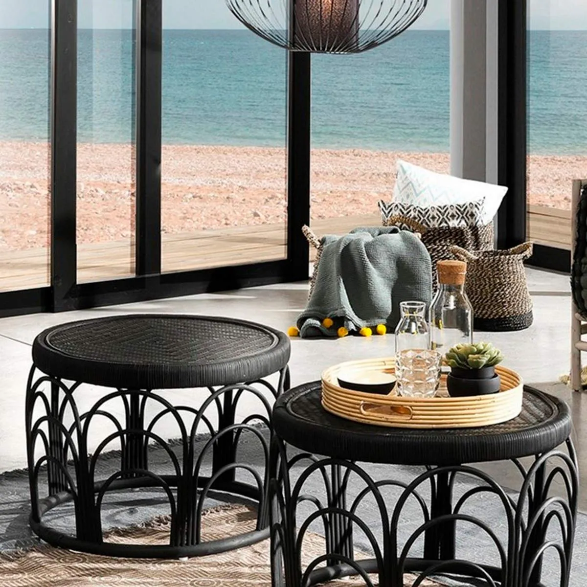 Tavolini Anil Tomasucci in rattan nero in una veranda sul mare