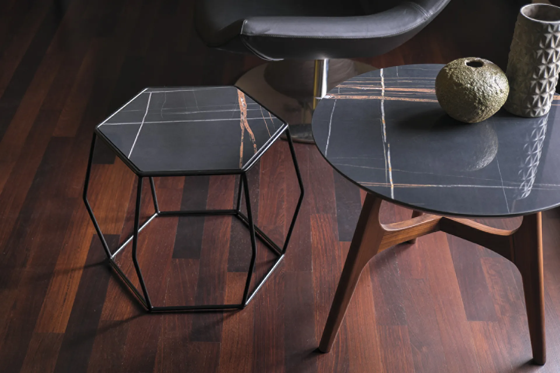 Tavolino esagonale Tosato 11.100 in metallo e gres su parquet scuro, accanto a un tavolino rotondo