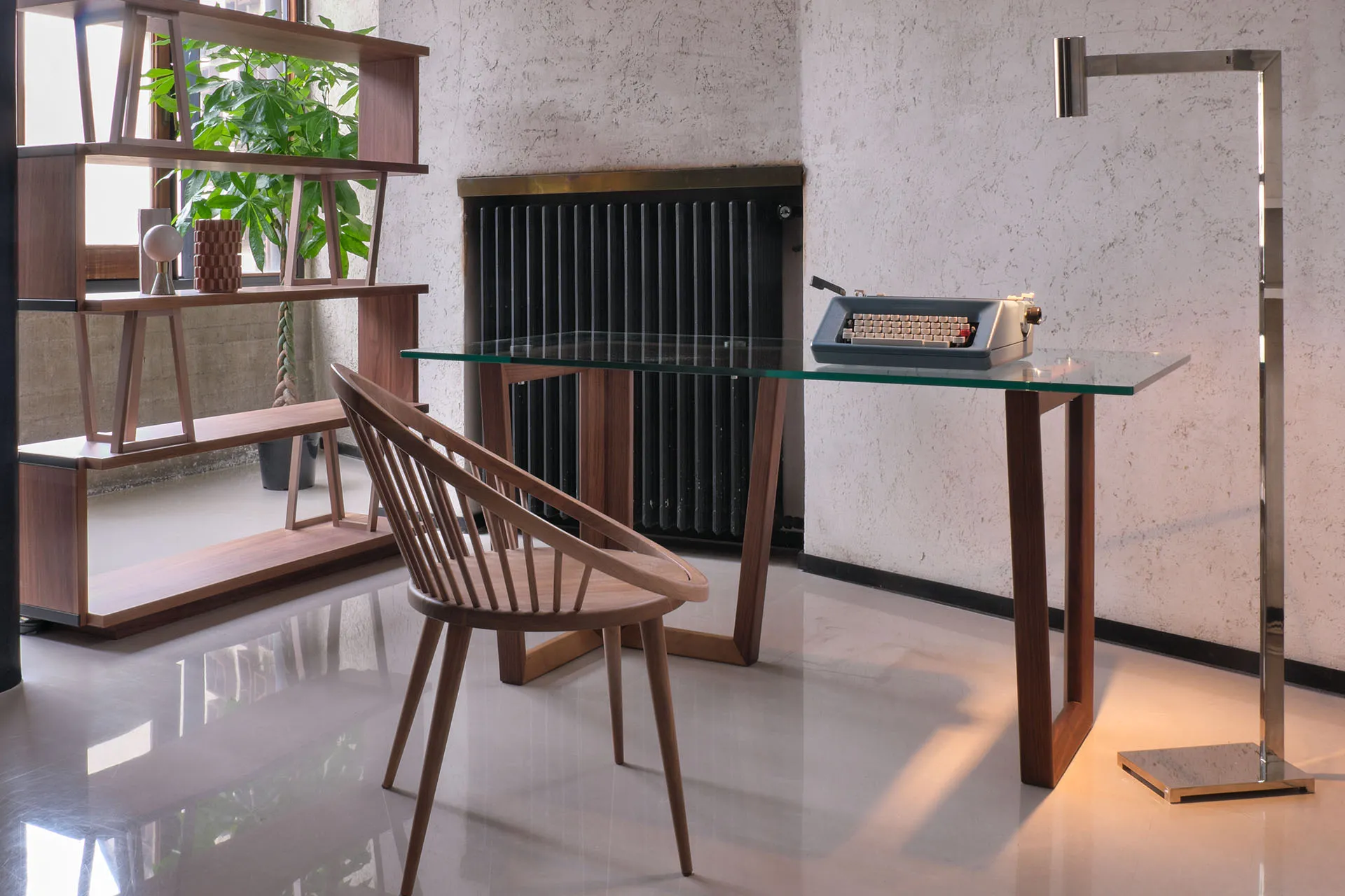 Scrivania Tosato 21.60 con piano in vetro in uno studio, con sedia in legno e libreria sullo sfondo